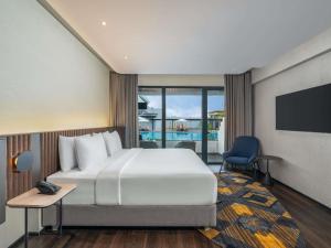a hotel room with a bed and a tv at Novotel Pontianak Convention Centre in Pontianak