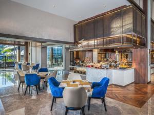 a restaurant with blue chairs and tables and a bar at Novotel Pontianak Convention Centre in Pontianak
