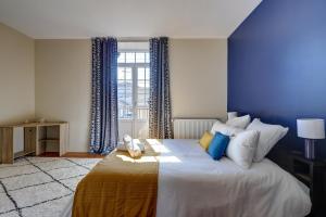 a bedroom with a large bed with a blue wall at La Maison des Prés - Maison bourgeoise de 1890 in Montceau-les-Mines