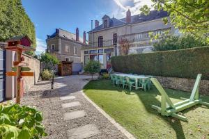 a garden with a table and chairs in front of a building at La Maison des Prés - Maison bourgeoise de 1890 in Montceau-les-Mines