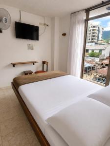 ein Schlafzimmer mit einem Bett und einem Fernseher an der Wand in der Unterkunft Hotel Armont Calarca in Calarcá