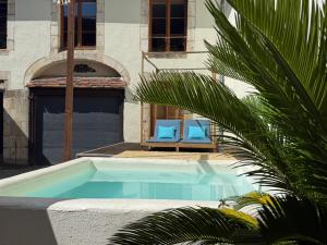 a swimming pool with two blue chairs and a palm tree at La Galerie - Mini Piscine - Bourges Originale in Bourges