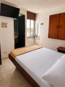 ein Schlafzimmer mit einem großen weißen Bett und einem Fenster in der Unterkunft Hotel Armont Calarca in Calarcá