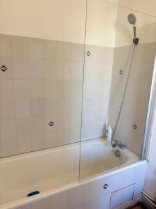a bathroom with a tub with a shower at Logement Angèle in Malesherbes