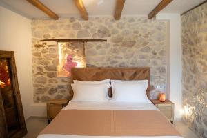 a bedroom with a bed and a stone wall at Penelope Suites With View Meteora in Kalabaka