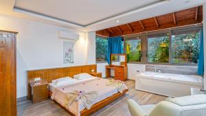 a bedroom with a bed and a couch and windows at Secluded Sea-View Family Escape Villa Bella 3 Lale in Üzümlü +59 photos