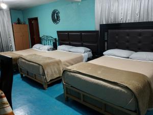 two beds in a room with blue walls at Hospedaje La Cienega in Zacatlán