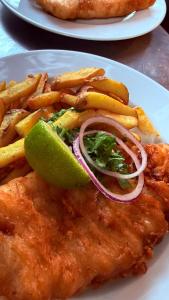 a plate of fish and french fries with a lime at Kârma Hôtel in Saint-Genis-les-Ollières
