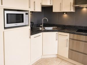 a kitchen with white cabinets and a microwave and a sink at apartment 2 miles from Maastricht in Lanaken