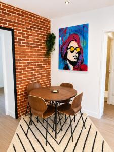 a dining room with a table and chairs and a painting at Brick - Loft design avec parking privé in Saint-Désir