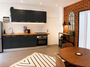 a kitchen with black cabinets and a wooden table at Brick - Loft design avec parking privé in Saint-Désir