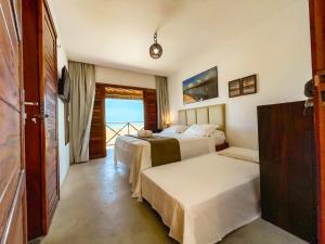 a hotel room with two beds and a balcony at Villa do Sol - Icaraí de Amontada in Icaraí