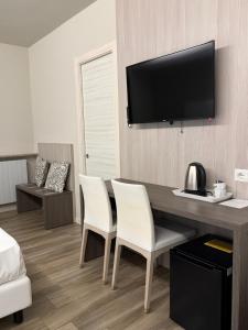 ein Zimmer mit einem Tisch, zwei Stühlen und einem Flachbildfernseher in der Unterkunft Hotel Riposo in San Pellegrino Terme