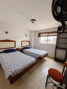 ein Schlafzimmer mit zwei Betten und einem roten Stuhl in der Unterkunft Hotel Armont Calarca in Calarcá + 14 Fotos