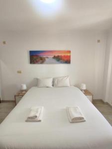 a bedroom with a white bed with a painting on the wall at Mivô - Alcochete Views & Comfort in Alcochete +32 photos