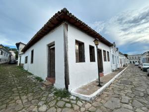 a white building with a roof on a street at Casa Beco do Sertão - Praça do Coreto in Goiás