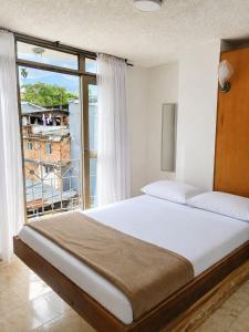 ein Schlafzimmer mit einem großen Bett und einem großen Fenster in der Unterkunft Hotel Armont Calarca in Calarcá