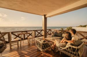 a couple sitting on a deck looking out at the ocean at Olivia Oceanfront Tulum in Tulum