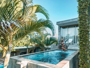 a woman standing in a swimming pool next to a house at Villa Los Laureles III, Private Pool, Nature Trails, Beaches in Esterillos Este