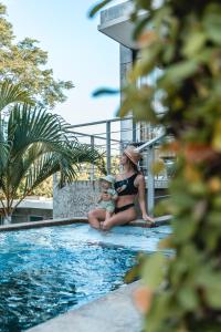 a woman holding a baby sitting next to a swimming pool at Villa Los Laureles III, Private Pool, Nature Trails, Beaches in Esterillos Este +29 photos