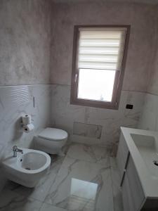 a bathroom with a toilet and a sink and a window at Valentina GuestHouse in Sestu