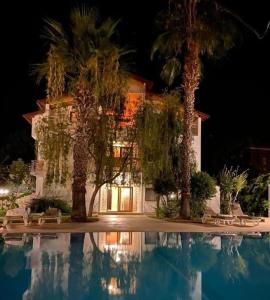 a house with palm trees in front of a swimming pool at Farmside OTEL in Fethiye