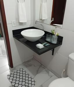 a bathroom with a bowl sink on a black counter at Apartamento próximo a Lagoa do Perola in Governador Valadares