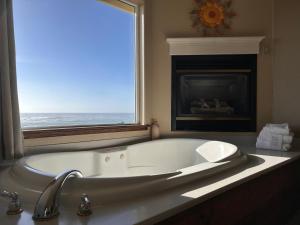 a white bath tub in a bathroom with a fireplace at North Cliff Hotel in Fort Bragg +39 photos