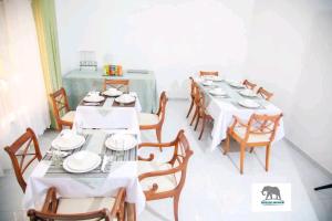 a dining room with white tables and wooden chairs at Dopiro Lodge and Gardens in Nyanda
