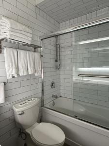 a white bathroom with a toilet and a bath tub at Dragon Gate Inn in Toronto +59 photos