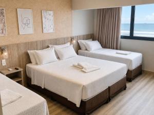 a hotel room with two beds and a window at Navega Beach Palace Hotel in Navegantes +101 photos