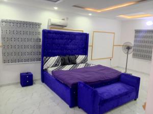 a bedroom with a purple bed and a fan at Four bedroom duplex in Lagos