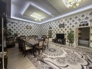 a dining room with a table and chairs and a television at Dacha by Bex Sueno in Samarkand