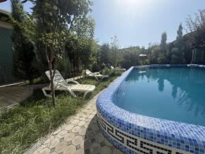 a swimming pool with two chairs next to a house at Dacha by Bex Sueno in Samarkand
