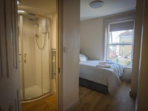 a bedroom with a shower and a bed and a window at East Bridge House in Enniskillen