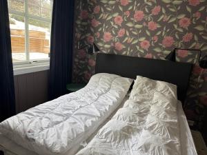 an unmade bed in a bedroom with floral wallpaper at The View in Sauda
