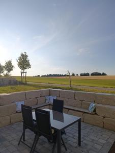a table and two chairs and a stone wall at Kapellenblick Auszeit mit Ausblick in Heroldstatt