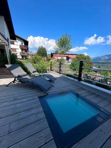 a deck with two chairs and a swimming pool at Appartamento Graziella in Castello di Fiemme