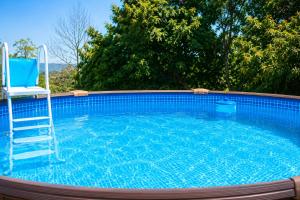 a swimming pool with a chair and a ladder in it at FINCA El LABRAO DE ALARDOS in Candeleda