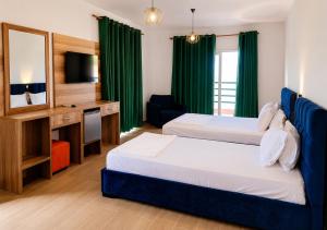 a hotel room with two beds and a television at Grecia's Dhermi in Dhërmi