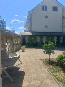a patio with a white building and a house at Pensiunea Lari in Baile Unu Mai