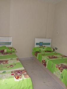 two beds in a room with green sheets at Cairo gust house in Alexandria