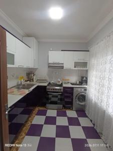 a kitchen with white cabinets and a checkered floor at Sheki Dream House in Sheki