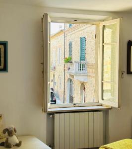 a teddy bear sitting on a bed looking out a window at Casa Da Cicia in Casiano