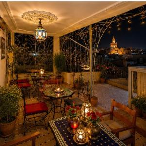 a patio with tables and chairs and a view of the city at Riad Fes Layan in Fez