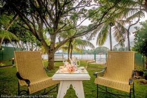 two chairs and a table with a tea set on it at serendipty lake villa in Panadura