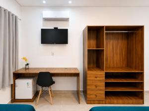 a room with a desk with a tv and a book shelf at Regine's Hotel in Itaquatiara