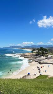 a beach with people on the sand and the ocean at Casa Marinho - Pé na praia in Saquarema