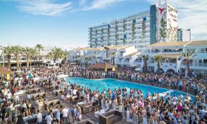 a large crowd of people standing around a swimming pool at Apt in Playa den Bossa next Ushuaia, beachfront, reliable host in Ibiza Town