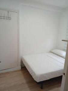 a white bedroom with a bed and a window at Imperial Tarraco Apartment in Tarragona